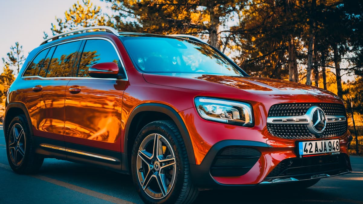 Stunning red Mercedes SUV parked on a serene forest road, ideal for automotive enthusiasts.